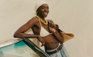 woman wearing a white bikini top, jeans, and a brown bag