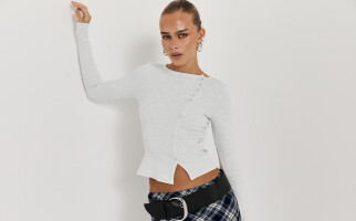 woman wearing a grey sweater and plaid skirt