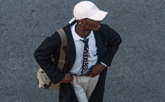 Person wearing a white baseball cap and coat with tie