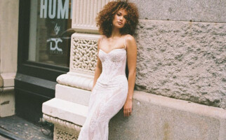 Woman wearing a white dress while leaning against a wall