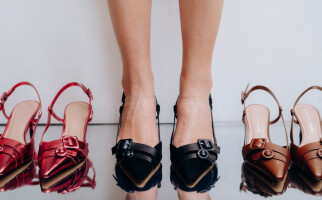 Person wearing a pair of black heels while standing beside a pair of red and brown heels