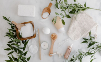 Various beauty and skincare products on a white table with leaves