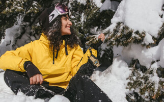 Woman sitting in snow while wearing Oakley goggles