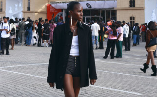 Woman walking while wearing a black jacket, white shirt, and black shorts