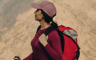 Woman wearing a pink hat and red shirt while carrying a backpack