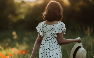 Girl walking through a field of flowers while wearing a polka-dot dress