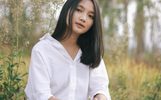Woman sitting in a field while wearing a white blazer